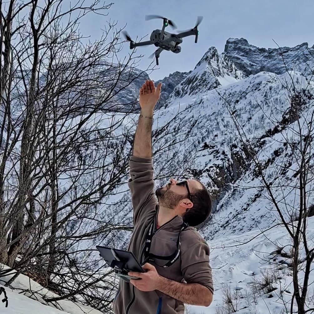 Décollage d'un drone depuis la main du télépilote dans un paysage de montagne